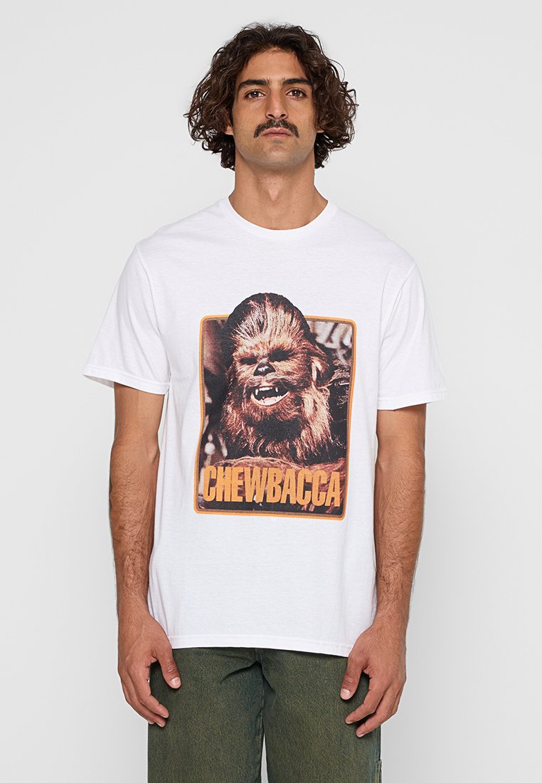 Vit bomullströja med en stor tryckt grafik av Chewbacca med text nedanför. Kort ärm och rund halsdesign.
