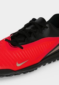 Κόκκινο και μαύρο αθλητικό παπούτσι Nike με μαύρα κορδόνια και υφή στην σόλα, σχεδιασμένο για εξωτερική αθλητική χρήση.