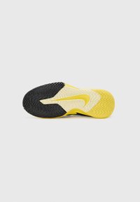 Sole of a sneaker featuring black rubber at the heel, yellow and white textured sections, and a subtle zigzag pattern on the tread.