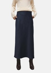 Jupe maxi bleu marine taille haute en tissu lisse, présentant une silhouette droite et sans embellissements visibles, accompagnée de bottes marron.