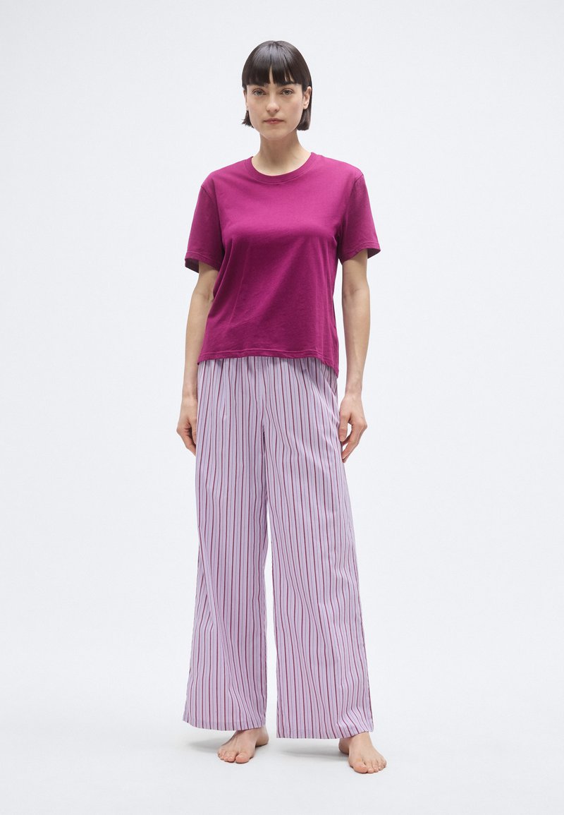 T-shirt à manches courtes fuchsia associé à un pantalon large rayé en violet clair et blanc. Le tissu semble doux avec une coupe décontractée.