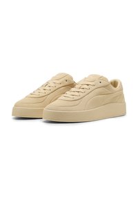 Zapatillas beige con un upper de ante suave, que cuentan con cordones redondeados, una suela de goma gruesa y una suela exterior texturada. Elementos de diseño minimalistas.