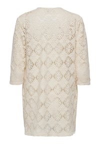 Lace tunic in light beige with a diamond pattern, 3/4 sleeves, round neckline, and loose fit, showcasing intricate cutouts throughout.