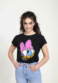 Sort bomulds t-shirt med et stort cartoon-design af Daisy Ducks ansigt med en lyserød sløjfe, blå øje og gul næb. Korte ærmer, afslappet pasform.