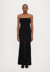 Black strapless dress with a fitted top and flowing pleated skirt, made of lightweight fabric. Features a soft texture and a long silhouette.