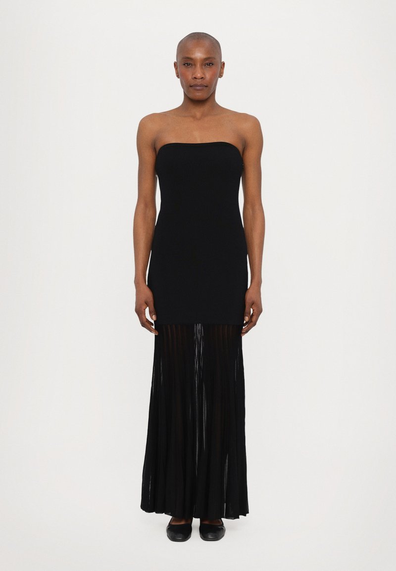 Black strapless dress with a fitted top and flowing pleated skirt, made of lightweight fabric. Features a soft texture and a long silhouette.