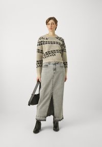 Beige kootud sviiter musta ahela mustriga ja "SUNDAY" tekstiga. Hall denimpikk seelik esi lõhiku ja kulunud äärtega. Mustad pahkluu saapad ja kott.