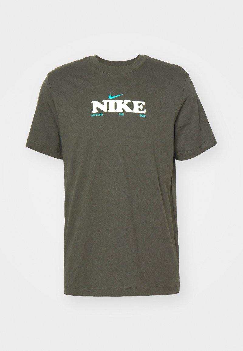 Oliwkowa bawełniana koszulka z krótkim rękawem, okrągłym dekoltem i wyraźnym logo "NIKE" w białym i akwamarynowym kolorze, z hasłem "NURTURE THE SOLE" poniżej.