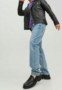 Svart läderjacka, lila hoodie, ljusblå jeans och svarta skor. Jackan har fickor med dragkedja, jeansen är raka. Klädesplaggen verkar vara avslappnade.