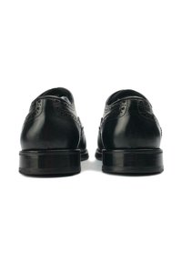Black leather dress shoes featuring a rounded toe, decorative broguing on the sides, and a stacked heel design.