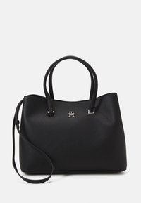 Bolso tote de cuero negro con un acabado texturizado, que cuenta con dos asas cortas y una correa para el hombro desmontable. Detalle del logo en plata en la parte frontal.