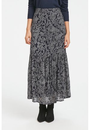 Woman wearing a black and white floral patterned midi skirt with a ruffled hem and black ankle boots, standing against a white background.
