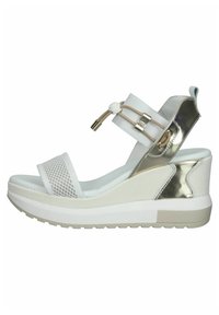 White wedge sandals with metallic accents, mesh upper, padded straps, and a textured sole. Features a cushioned insole for comfort.