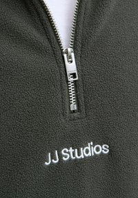 Dark green fleece quarter-zip pullover featuring a silver zipper and embroidered "JJ Studios" in white. Soft texture and casual design.