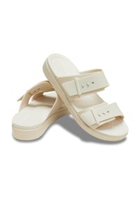 Beige sandals with two adjustable straps, made of smooth plastic material. Contoured footbed with a textured surface for comfort.
