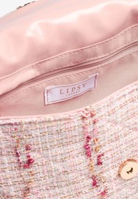 Roosa tweed käsipungaga, millel on kuldse lõime aktsendid, sile roosa vooder ja lukuga tasku, millel on "Lipsy London" silt. Ümmargune klamber.