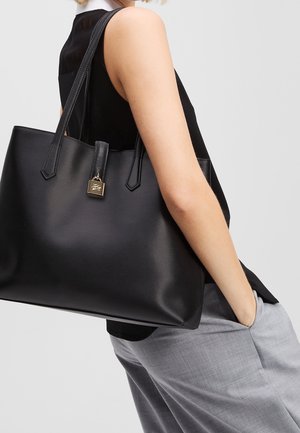 Schwarze Leder-Tote mit doppelten flachen Tragegriffen, glatter Textur, rechteckiger Form und einem goldenen Schlossakzent an der Vorderseite.