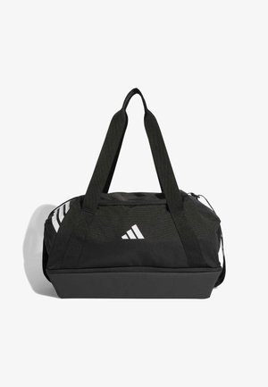 Sac de sport noir avec double poignée, fabriqué en tissu résistant. Présente un logo Adidas blanc et trois bandes blanches sur un côté. Ouverture zippée.