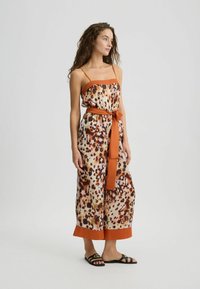 Satijnen jumpsuit in een panterprint patroon met oranje accenten, met een aansluitend lijfje, verstelbare bandjes en een gestrikte taille.