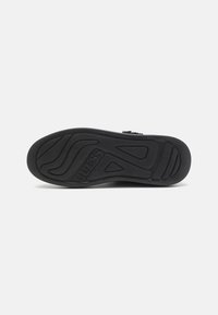 Suola di scarpa nera in gomma con un motivo testurizzato, caratterizzata dal logo "GUESS" e scanalature distintive per la trazione; forma piatta e larga.