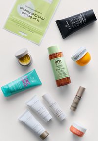 Blandade hudvårdsprodukter: grön toner, blå och vita tuber, gula och svarta burkar, mönstrad förpackning. Olika former och storlekar.