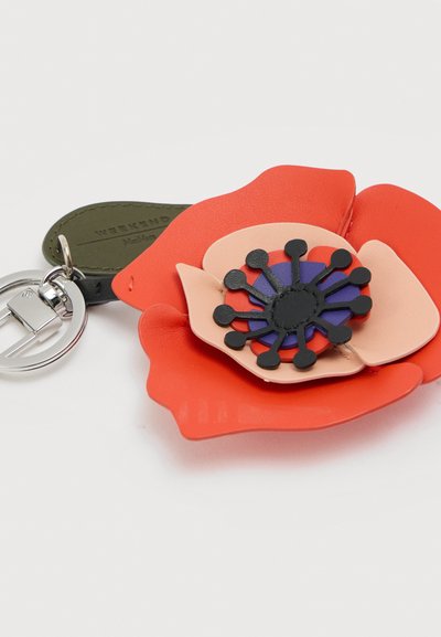 Μπρελόκ με λουλούδι από στρωμένο κόκκινο και ροδακινί δέρμα, με μαύρο και μωβ κέντρο, προσαρτημένο σε ασημένιο δαχτυλίδι και σκούρο πράσινο δερμάτινο ταμπελάκι.