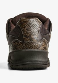 Barna sportcipő sarok, dombornyomott kígyóbőr mintával és texturált párnázással, fehér háttéren.