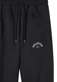 Czarne dresy z elastycznym paskiem w talii, regulowanym sznurkiem, bocznymi kieszeniami oraz małym haftowanym logo "Champion" na udzie.