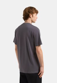 T-shirt grigia a girocollo realizzata in tessuto morbido, maniche corte, vestibilità regolare, con una texture liscia e senza motivi o decorazioni visibili.