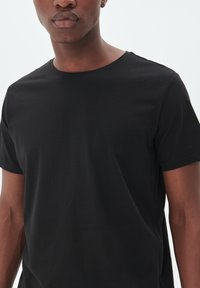 Sort crew-neck T-shirt lavet af blødt stof. Korte ærmer, almindelig pasform, glat overflade uden synlige mønstre eller detaljer.