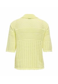 Haut court en crochet jaune pâle à manches courtes avec motif ajouré et bords festonnés, vu de dos.