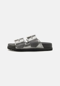 Metallisk grå slidesandal med to justerbare stropper, flat svart såle og heksagonalformede detaljer. Tekstilt overmateriale.