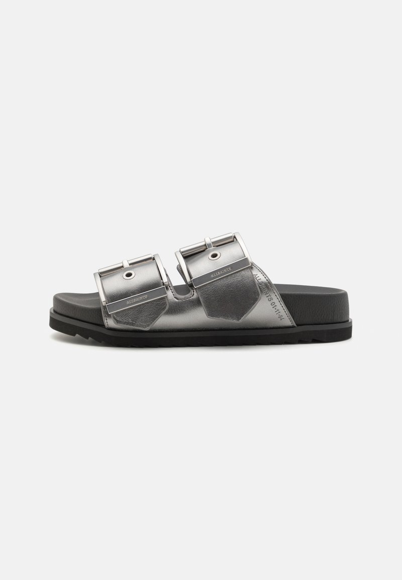 Metallisk grå slidesandal med to justerbare stropper, flat svart såle og heksagonalformede detaljer. Tekstilt overmateriale.