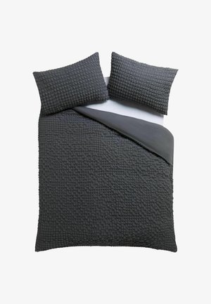 Dunkelgraues, strukturiertes Decken-Set mit zwei passenden Kissenbezügen auf einem Bett, eine Ecke zurückgefaltet, um die glatte Unterseite zu zeigen.