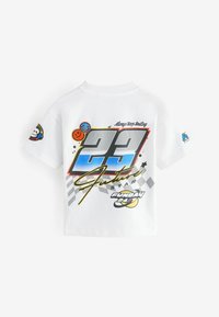 Bílý bavlněný tričko s barevným grafickým designem, na kterém je číslo "22", usmívající se emoji a text, včetně "Vždy se usmívej" a "Funday 24/7."