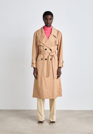 Beige trenchcoat mit breiten Revers, doppelreiher Knöpfen und gebundenem Taillengürtel. Kombiniert mit einem rosa Oberteil und cremefarbenen Hosen. Glatte Textur.