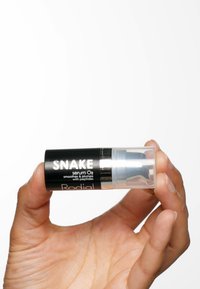 Bouteille de sérum cylindrique noire avec un sommet pompe transparent, étiquetée "SNAKE serum O2," avec des accents argentés et une finition lisse.