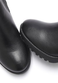 Crne gležnjače od glatke kože s okruglim vrhom, debelim teksturiranim gumenim potplatom i minimaličkim dizajnom bez vidljivih dijelova.