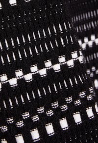 Tissu à motif géométrique noir et blanc, comprenant des formes variées telles que des rectangles et des lignes, surface texturée, tissu tissé dense.