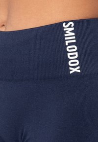 Leggings sportivi blu navy con texture a coste, con logo bianco "SMILODOX" sulla cintura per l'identificazione del marchio.
