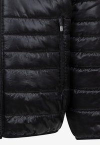 Μαύρο μπουφάν πούφ με κεντητή υφή, διαθέτει τσέπη με φερμουάρ στο πλάι και λείο ύφασμα. Ελαφρύ με άνετη εφαρμογή και σκούρο χρώμα.