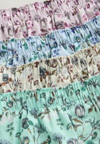 Quatre ceintures en tissu rassemblées avec de petits motifs floraux dans des tons pastel de rose, bleu, crème et vert menthe.