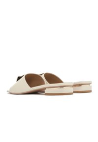 Beige schuifsandalen van soepel leer met open tenen, voorzien van een lage blokhak met een contrasterende band en een minimalistisch ontwerp.