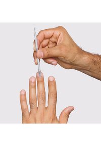 Rustfrit stål neglebåndsværktøj holdt over en hånd med lys brun hud og pænt trimmede negle på en neutral baggrund, der viser præcision.