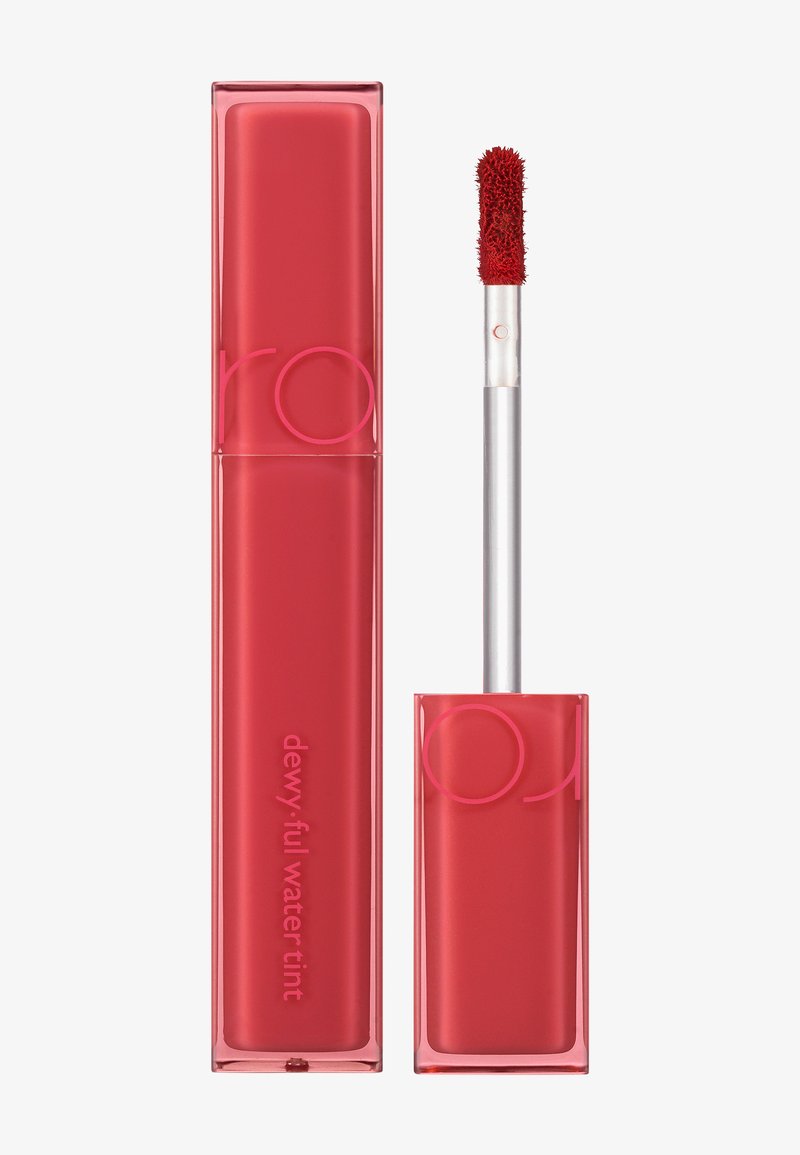 Teinture à lèvres liquide rouge dans un tube rectangulaire transparent avec des lettres roses. Comprend un applicateur en forme de pied de cerf avec une pointe texturée.