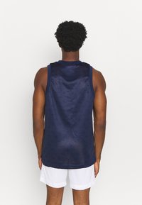 Tmavě modrý sportovní tílko bez rukávů z jemné síťoviny, s lehkou tkaninou, kulatým výstřihem a zaobleným lemem. Vzorkovaná textura přidává zajímavý detail.