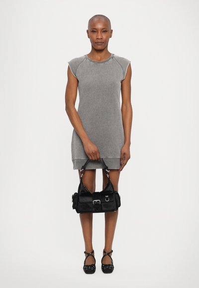 Grå kortærmet kjole med afslappet pasform, parret med en sort skuldertaske med spænde. Modellen har sorte sko med prikker på.