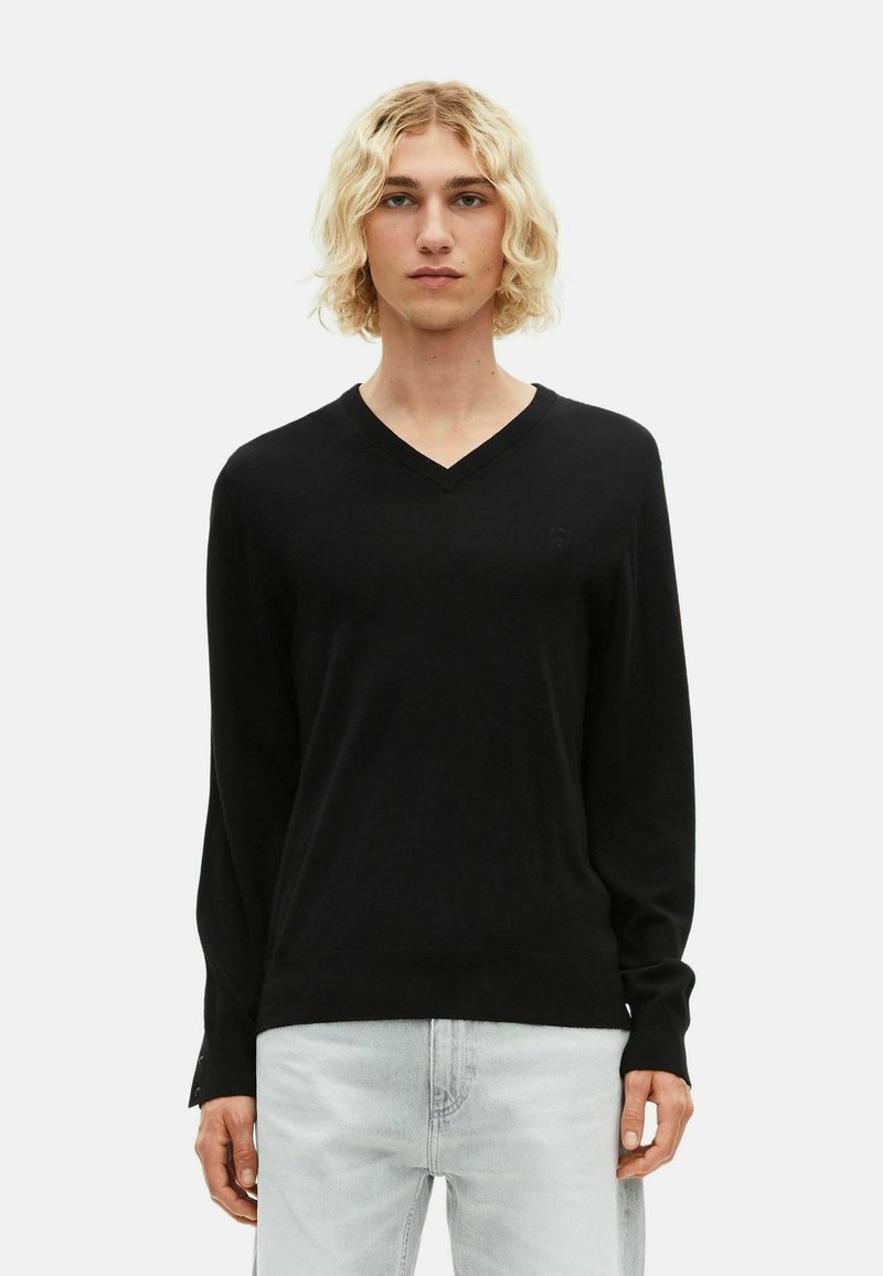 Suéter negro de cuello en V con mangas largas, hecho de una tela suave. Presenta un logo sutil en el pecho y puños y dobladillo acanalados.