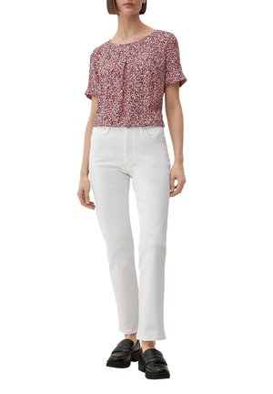 Kurze blauen Bluse mit rotem Blumenmuster, kombiniert mit weißen geraden Jeans und schwarzen Mokassins. Der Stoff scheint leicht und strukturiert zu sein.
