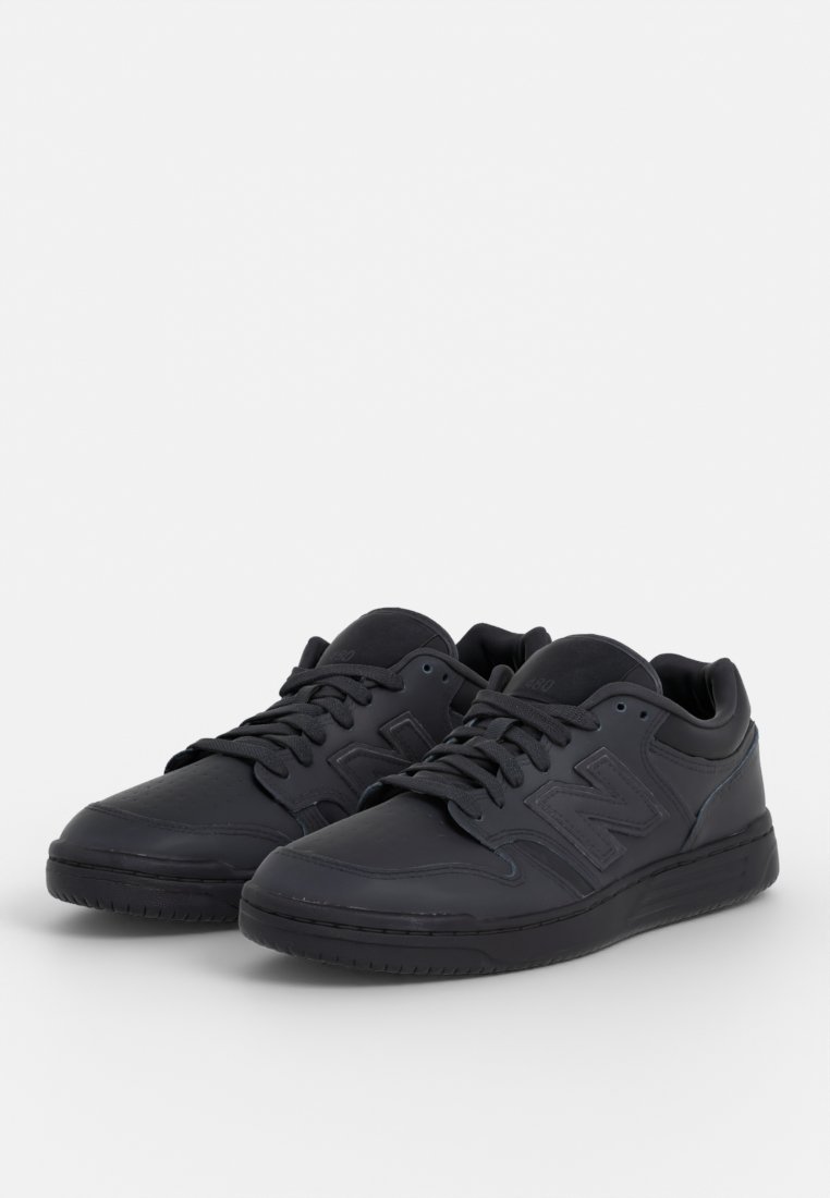 Baskets en cuir noir avec un design bas, présentant une finition texturée, un système de laçage solide et un logo "N" en relief sur le côté.